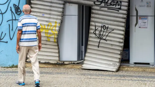 Homem observa loja arromabad e saqueada