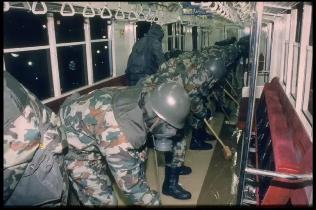 Equipos del Ejército nipón limpiando vagones del metro tras el ataque de 1995.