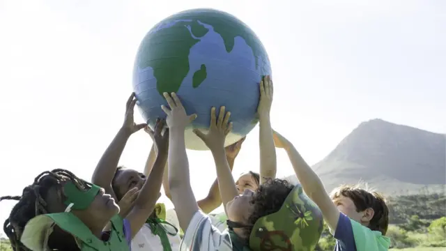 Varios niños sujetan un globo terráqueo en alto