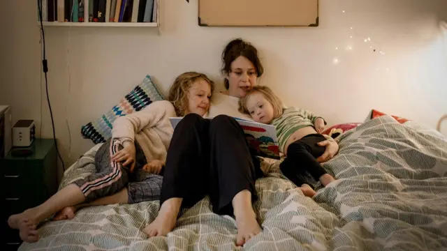 Madre leyéndole a sus hijas