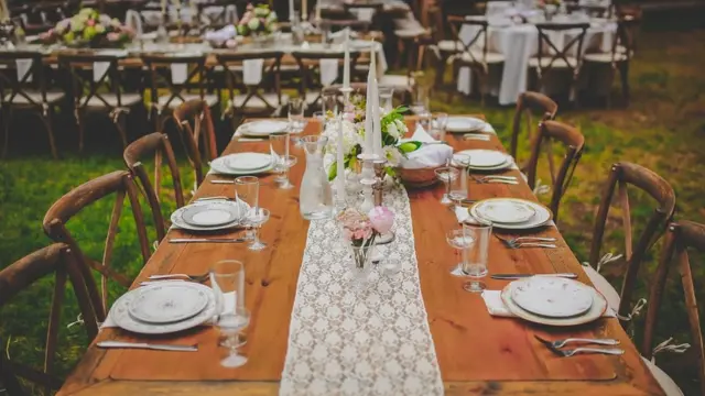 Outdoor banquet tables at dusk, beautifully decorated with lace, flowers and candles