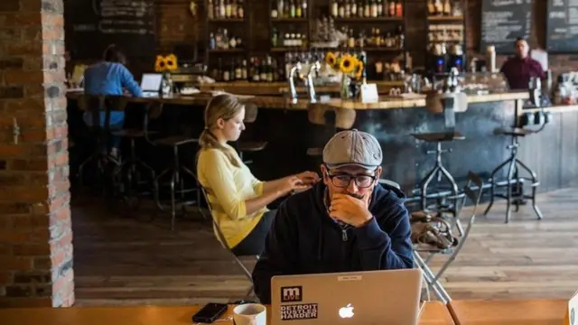 شاب يعمل من مقهى على جهاز كمبيوتر محمول