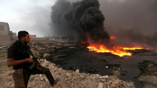 Membro das forãsfunmania slotsegurança iraquianas observa fumaça e fogo saindofunmania slotum poçofunmania slotpetróleo incendiado por combatentes do Estado Islâmicofunmania slotQayyarah