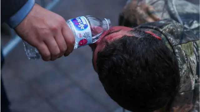 পানি দিয়ে পেপার স্প্রে ধুয়ে ফেলছেন এক বিক্ষোভকারী।