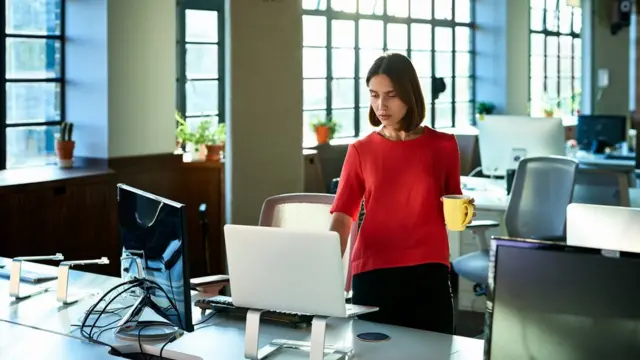 Mulher chega cedo ao trabalho quando escritório ainda está vazio