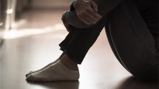 Mwanamke akiwa amekumbatia miguu yake