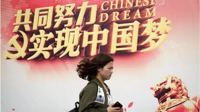一名妇女走过“实现中国梦”的宣传广告牌