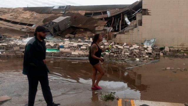 Dos personas pasan delante de un edificio destruido tras el paso del huracán Laura.