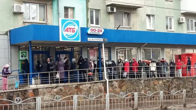 દુકાનની બહાર લાઇનમાં ઊભેલા લોકો