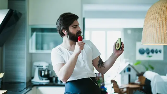 Un hombres canta en la cocina usando un pimiento como micrófono.