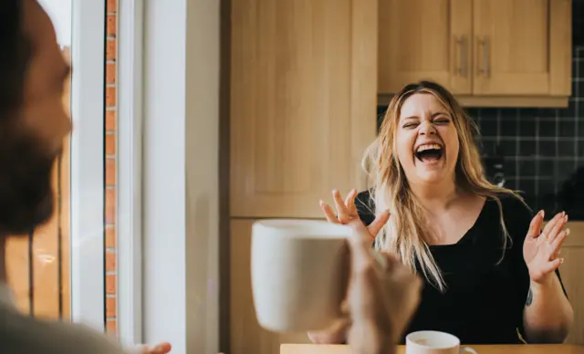 Una mujer ríe mientras conversa con un hombre