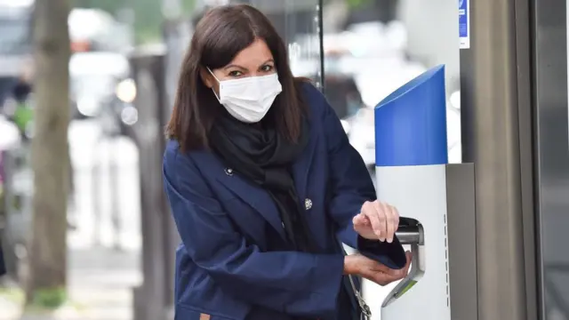 Paris Mayor Anne Hidalgo, wearing a protective facemask, rubs her hands as she inaugurates a public gel dispenser