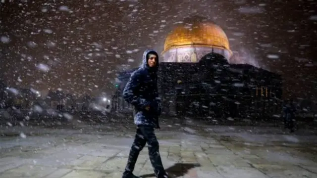 عابر أمام قبة الصخرة في المسجد الأقصى بالقدس بينما الصقيع ينهمر