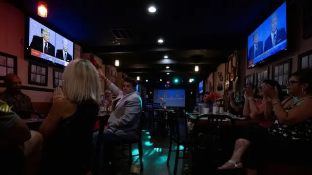 Personas miran el debate en un local