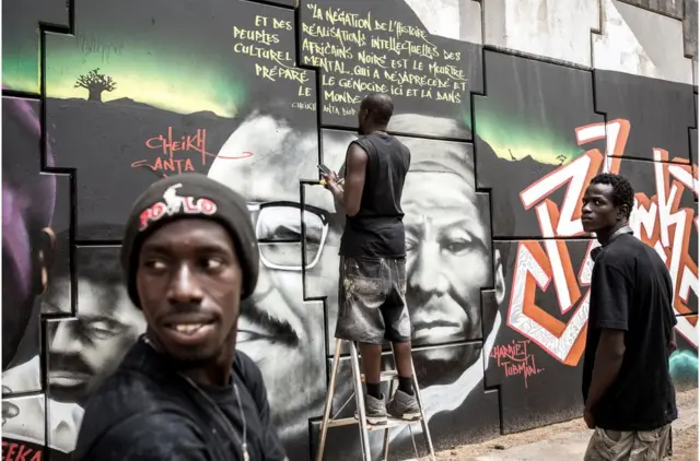 Wani memba na kungiyar Radikal Bomb Shot (RBS), na kasar Senegal, ya na zana hoton nuna goyon baya ga Amurkawa 'yan Afrika masu fafutukar yaki da nuna wariyar launin fata, wato kungiyar Black Lives Matter Matter a Dakar ranar 15 ga watan Yuni 2020.