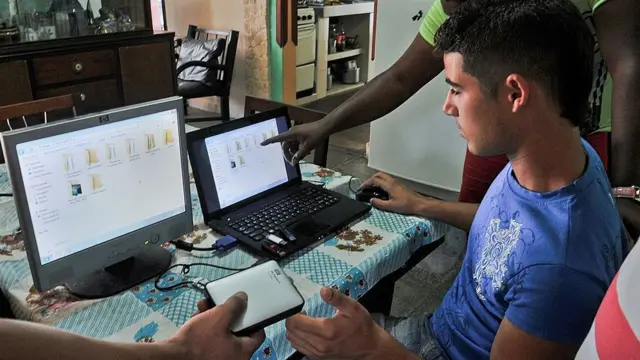 Cubanos reparando computadoras.