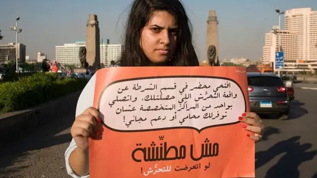 فتاة تحمل لافتة تشجع على الإبلاغ عن التحرش
