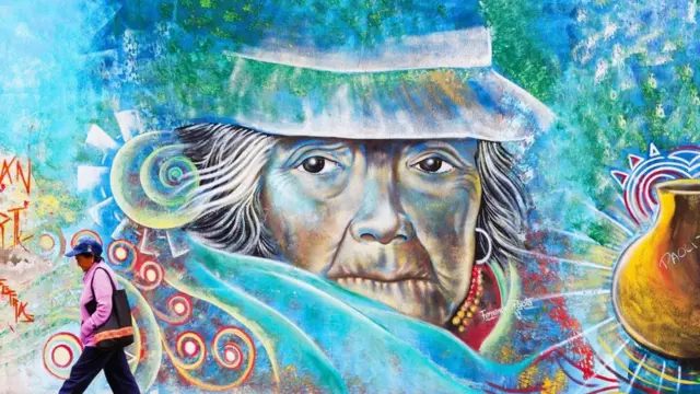 Una persona camina frente a un colorido grafiti en Ecuador