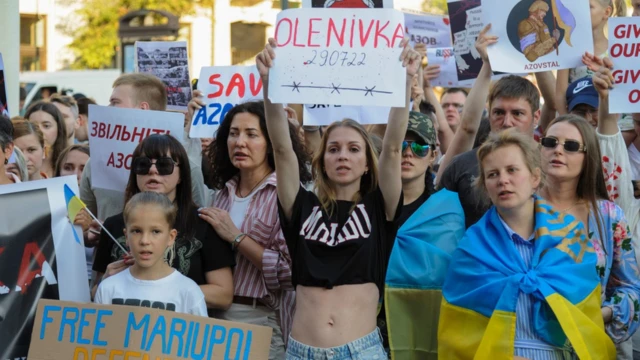 Ukrainian protesters hold placards about Olenivka