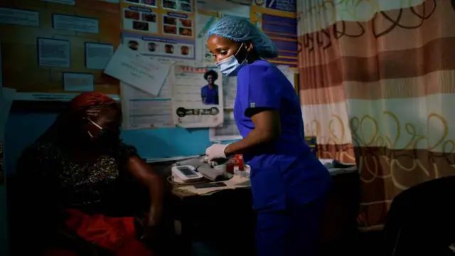 Ma'aikaciyar jinya ta sa kai, Anita Thumbi daga hagu wacce aka zaɓa a matsayin mamba a majalisar dokoki a lardin gwamnatin Nairobi, tana kula da wata mara lafiya don nuna wa mutane yadda ake kare kai daga kamuwa da cutar korona a wata cibiyar lafiya da ke Waithaka, a ranar 12 ga watan Mayu 2020, a yayin bikin ranar ma'aikatar jinya ta duniya.
