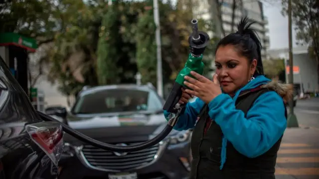 Trabajadora de gasolinera reponiendo combustible.