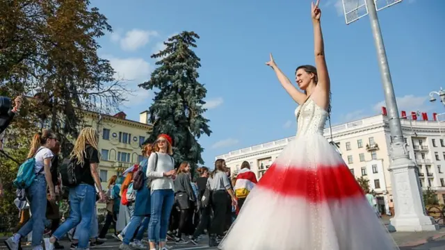 زن معتزض با پوشیدن لباس سفید و قرمز در تظاهرات ضد دولتی