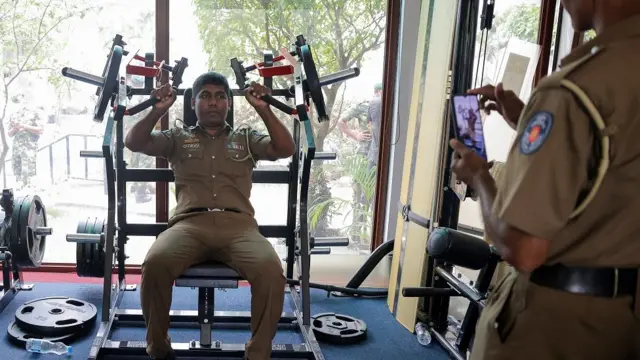 Un agente policial prueba equipos del gimnasio de la casa presidencial, un día después de que los manifestantes ingresaran al edificio.