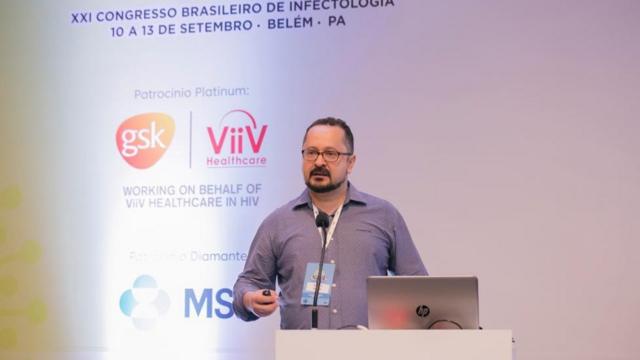 Pasqualotto fala ao microfone,apk da betanopé,apk da betanoconferência — com painel do evento ao fundo