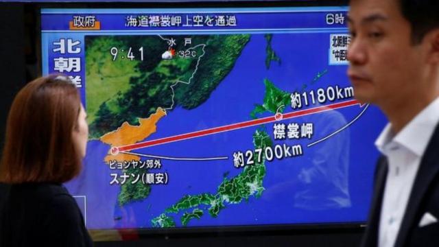 Pessoas olham uma TV que traz noticiário em japonês sobre o míssil norte-coreano