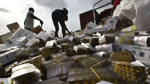 Une photo prise au cimetière de la commune d'Abobo à Abidjan le 10 mars 2017 montre des faux médicaments chinois alors que des personnes déchargent des boîtes de médicaments contrefaits d'un camion.