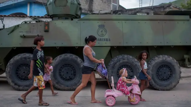 Família com crianças passasite para ver escanteiosfrente a veículo militar