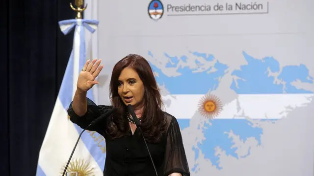 Cristina Fernández de Kirchner da un discurso frente a un mapa de las islas Malvinas/Falklands con los colores de la bandera argentina