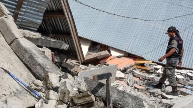 Petugas memeriksa rumah yang hancur akibat gempa berkekuatan 6,4 pada skala Richter. Lebih seribu rumah dilaporkan rusak, disamping belasan orang meninggal dan ratusan pengungsi.