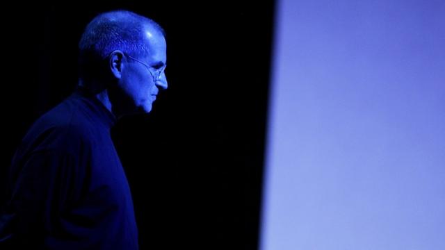 Steve Jobs iluminado por luz azul em evento de apresentação da Apple