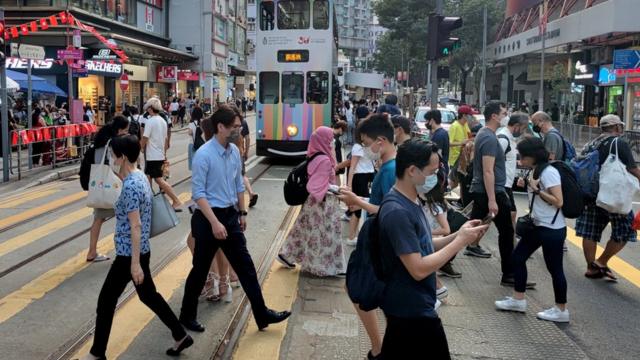 香港湾仔庄士敦道上的过路市民与靠站电车（中新社图片4/10/2022）
