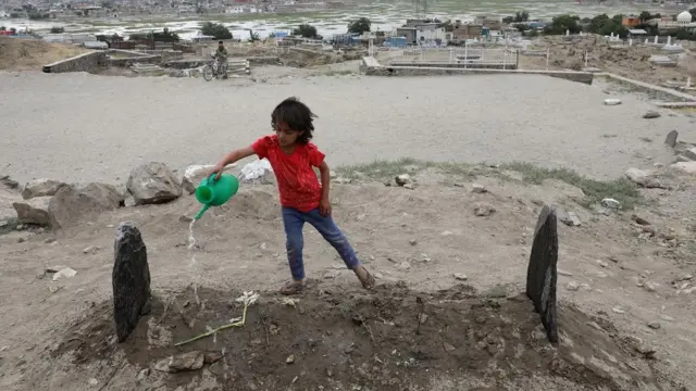 دختر بچه‌ای روی قبر فاطمه خلیل آب می‌پاشد