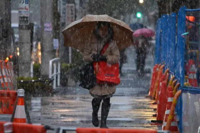 A woman walks through snow in Tokyo