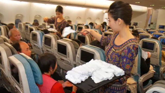 Funcionárias da Singapore Airlines distribuem toalhas para passageiros