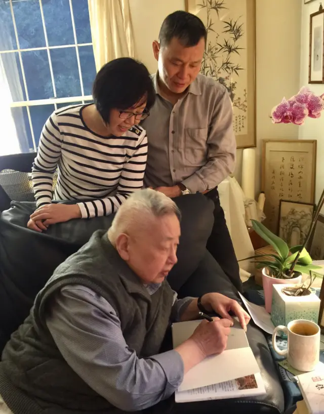 《南方都市报》前总编辑程益中(后)与夫人陈君英(中)在余英时(前)家中观看余教授在书上题字(12/2018)