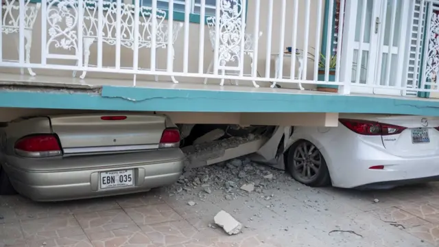 Una casa colapsada encima de dos autos.