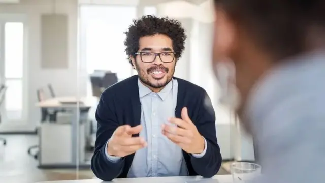 Un hombre conversa con otro en una oficina
