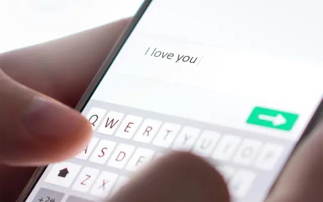 Une personne qui écrit I love you sur un téléphone portable