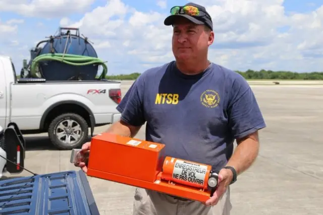 Un hombre sostiene una caja negra del avión