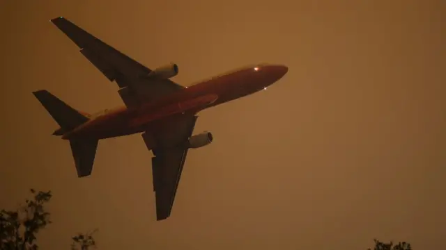 Un avión vuela contra un cielo ennegrecido.