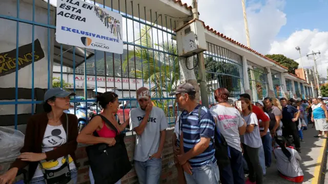 Una fila de gente a la puerta de un supermercado