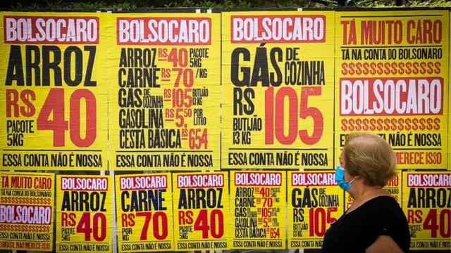 Idosa passa por cartazes da campanha 'Bolsocaro', que protesta contra a altarealsbet cnpjpreços no governo Bolsonaro