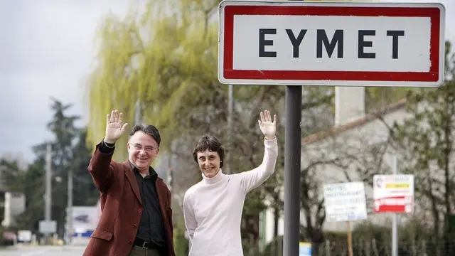 Мужчина и женщина на фоне дорожного указателя с надписью "Эме"