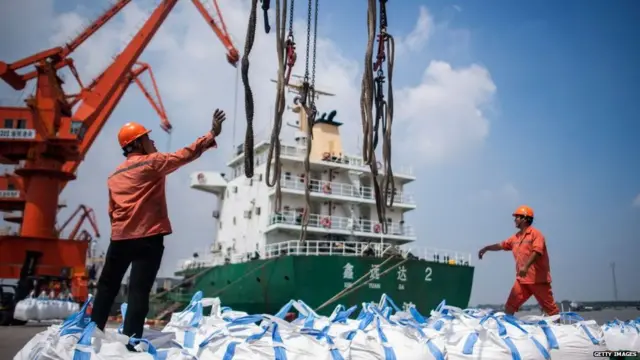 August 7, 2018 shows workers unloading bags of chemicals at a port in Zhangjiagang in China's eastern Jiangsu province. - China's trade surplus with the United States