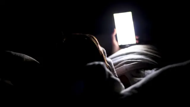Une personne regardant un téléphone portable au lit