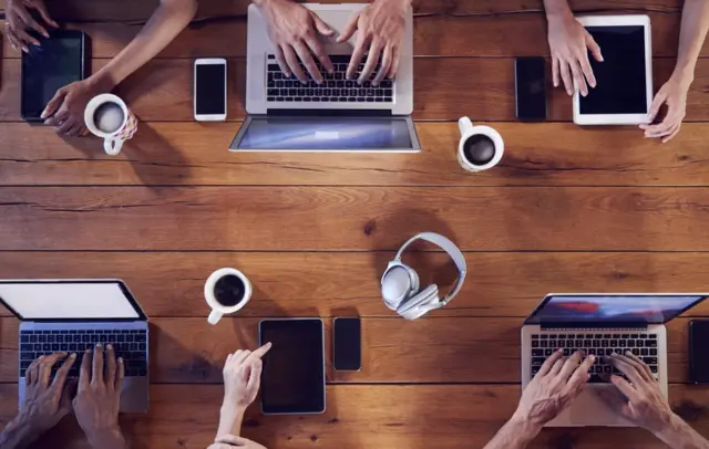 Grupo de millenials trabajando en sus laptops a escasa distancia.